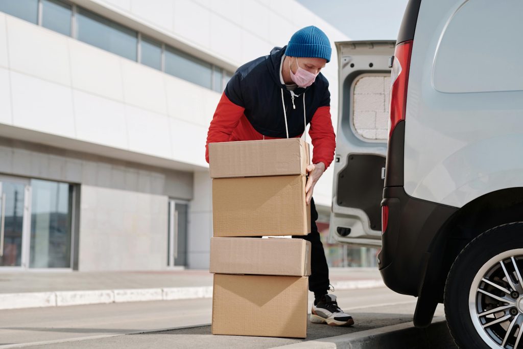 A picture of a courier unloading boxes from a van